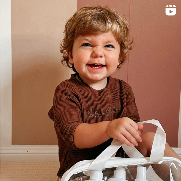 Child holding a clear bag with Little Lane haircare products
