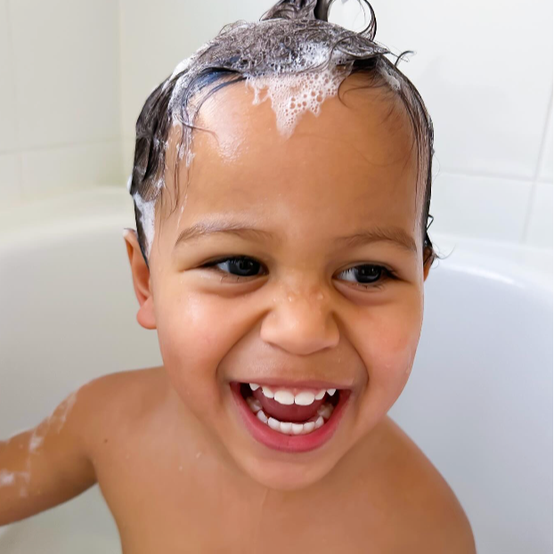 Child with shampoo on head in a bathtub
