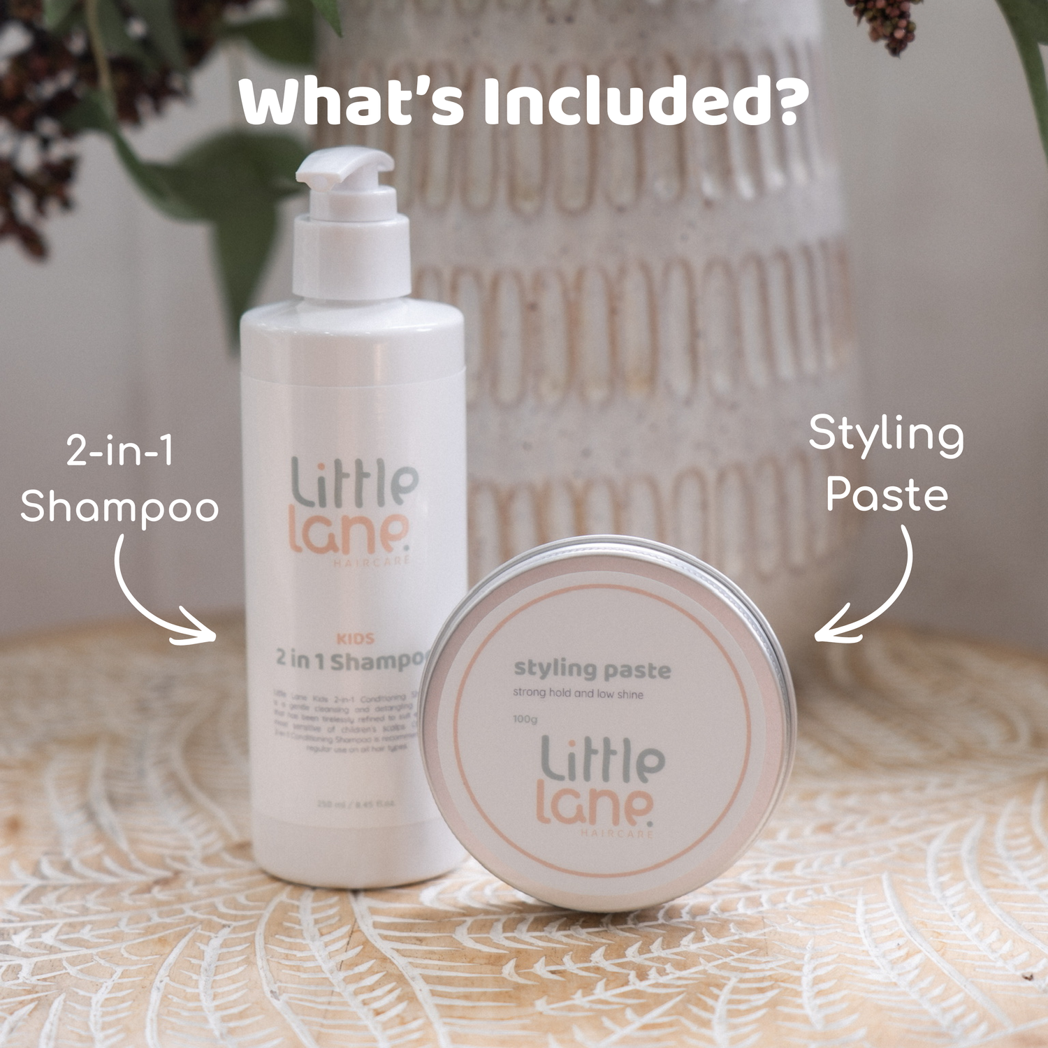 A bottle of Little Lane Kosmetics 2-in-1 Shampoo and a round tin of Styling Paste displayed together on a patterned surface with decorative background elements. White text overlays read &